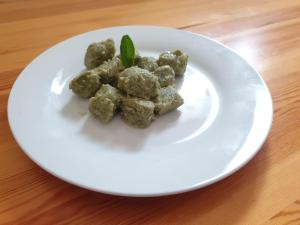 a white plate with meatballs on a wooden table at Agriturismo Fattoria Dalcastagnè in Torcegno