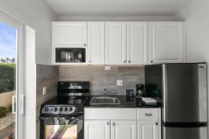 a kitchen with white cabinets and a stainless steel refrigerator at Elizabeth House Inn in Deerfield Beach