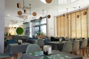 um restaurante com mesas e cadeiras azuis e janelas em Family Resort Sarbinowo em Sarbinowo