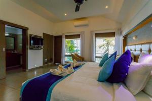 een slaapkamer met een groot bed met blauwe en witte kussens bij Kappad Beach Resort in Kappad