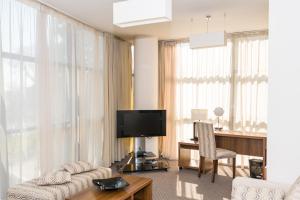 a living room with a couch and a table and a television at Hotel Burgas in Burgas