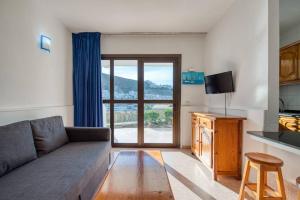 sala de estar con sofá y cocina con ventana en Huertas del Nublo Vivienda Vacacional, en Puerto Rico de Gran Canaria