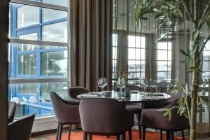 a dining room with a table and chairs and windows at Quality Airport Hotel Stavanger in Sola