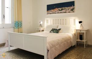 a white bedroom with a white bed and a painting at Sa Domu de Ajaja Apartments in Cagliari