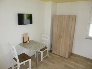 ein kleines Zimmer mit einem Tisch und einem Holzschrank. in der Unterkunft Pension am Peeneufer UG in Wolgast