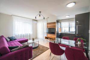 a living room with a purple couch and a glass table at Sprint Apartman in Siófok