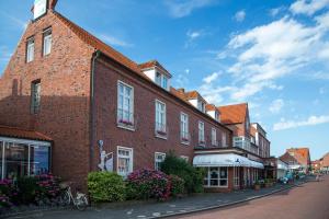 a red brick building on a street with flowers at Nordseehotel Freese in Juist