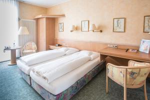 a large bed in a hotel room with a desk at Nordseehotel Freese in Juist +24 photos