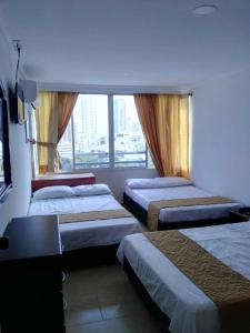 Habitación de hotel con 3 camas y ventana en Apartamento 1101 Edificio Nuevo Conquistador, en Cartagena de Indias