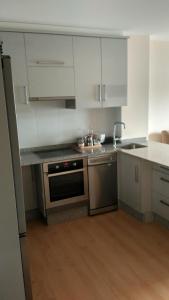 a kitchen with stainless steel appliances and white cabinets at Apartamento Corcubion Playa de Quenxe in Corcubión