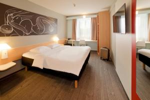 a hotel room with a large bed with white sheets at ibis Jena City in Jena