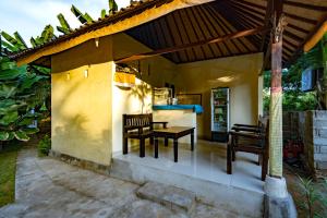 un patio con mesa y sillas bajo un techo en Pemuntalan Guesthouse, en Nusa Lembongan