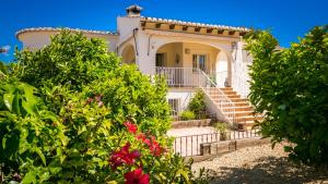une maison blanche avec des escaliers et des fleurs dans l'établissement Casa Los Pinos, à Benissa