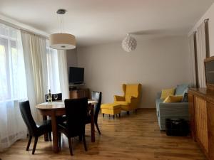a living room with a dining room table and yellow chairs at Charlotte by Q4Apartments in Gdańsk