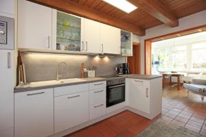 uma cozinha com armários brancos e um forno com placa de fogão em Fachwerkhaus em Ahrenshoop