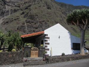 une petite maison blanche avec une montagne en arrière-plan dans l'établissement Casa Gorreta, à Jinama