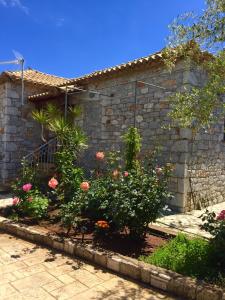 a garden with flowers in front of a stone building at Mouses Apartments-Kardamyli in Kardamili