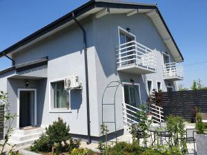 a white house with a balcony and a table at VillaGrey Residence Tunari in Tunari