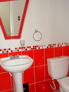 Baño rojo con lavabo y aseo en Hostal Universal Huaraz, en Huaraz