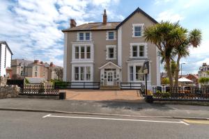 a large white house with palm trees in front of it at Lansdowne House with Private Car Park in Llandudno