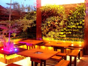 een patio met houten tafels en een tuin met planten bij Richard's Home in Pontianak