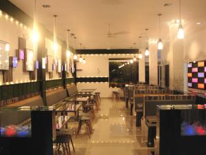 a dining room with tables and chairs and lights at Richard's Home in Pontianak