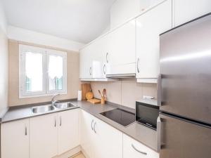 a kitchen with white cabinets and a stainless steel refrigerator at Chalet La Rosa in Cala Blanca