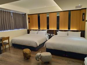 a bedroom with two beds and a table and chairs at Lantan Fanyue Inn in Chiayi City