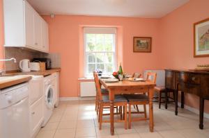 een keuken met een tafel en stoelen en een raam bij Rhoda`s Cottage in Creggans