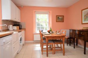 a kitchen with a table and chairs and a window at Rhoda`s Cottage in Creggans