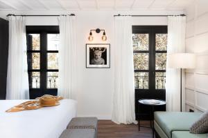 una camera con tende bianche e un letto di Yurbban Ramblas Boutique Hotel a Barcellona