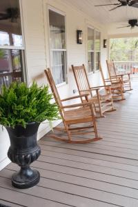 une terrasse couverte avec des fauteuils à bascule et un vase orné d'une plante. dans l'établissement Stonehill's Farmhouse, à Accord