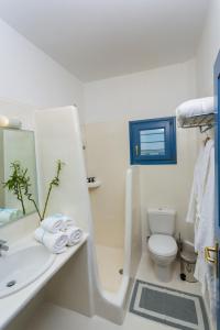 a white bathroom with a sink and a toilet at Acquamarina Resort in Chrissi Akti