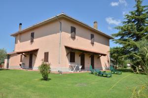 un grande edificio con due sedie verdi in un cortile di Agriturismo San francesco a Orbetello