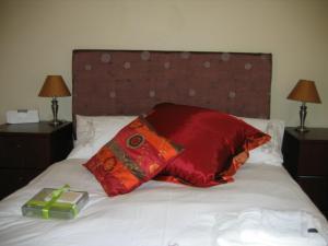 Una cama con una almohada roja y una caja verde. en Malleson Garden Cottage, en Ciudad del Cabo