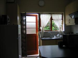 cocina con puerta, fregadero y nevera en Malleson Garden Cottage, en Ciudad del Cabo