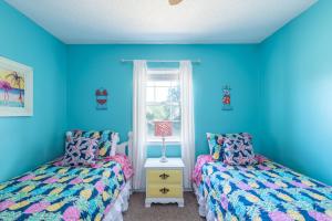 two beds in a room with blue walls at Seawalk Cottage in Tybee Island