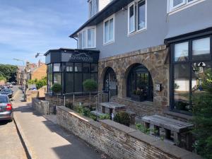 um restaurante com bancos fora de um edifício em The Sunningdale em Bamburgh