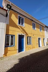 a yellow house with a blue door on a street at CASA AMARELA in Avis