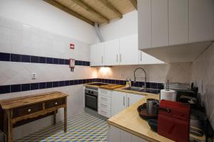 a kitchen with white cabinets and blue and white tiles at CASA AMARELA in Avis