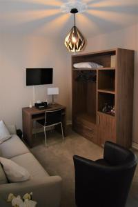 a living room with a couch and a desk and a television at Hotel Le Saint-Yves in Le Tréport