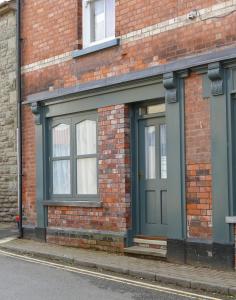 um edifício de tijolos com uma porta verde numa rua em 2 Bell Street em Talgarth