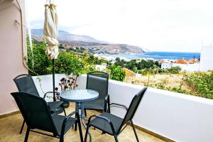 einen Tisch und Stühle auf einem Balkon mit Aussicht in der Unterkunft Maltabe Studios in Ándros