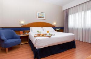 um quarto de hotel com uma cama e uma cadeira azul em Agumar em Madri