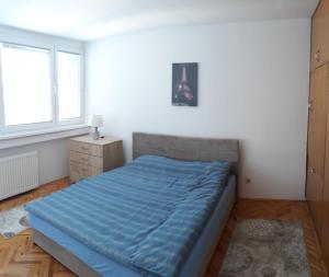 - une chambre avec un lit bleu et 2 fenêtres dans l'établissement Apartment Ambrela 2, à Sarajevo