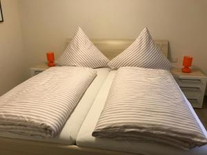 a bed with two pillows on it with two orange candles at Pension zum Butterpatt in Sassenberg