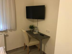 a desk with a chair and a television on a wall at Pension zum Butterpatt in Sassenberg