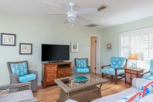 a living room with a flat screen tv and blue chairs at Somewhere in Time Too in Tybee Island
