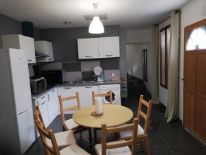 a kitchen with a table and chairs and a kitchen with white cabinets at Maison Duplex & Appartement sur cour in La Ferté-Gaucher