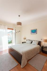 a white bedroom with a large bed and a window at Apartamento Praia São Martinho do Porto in São Martinho do Porto